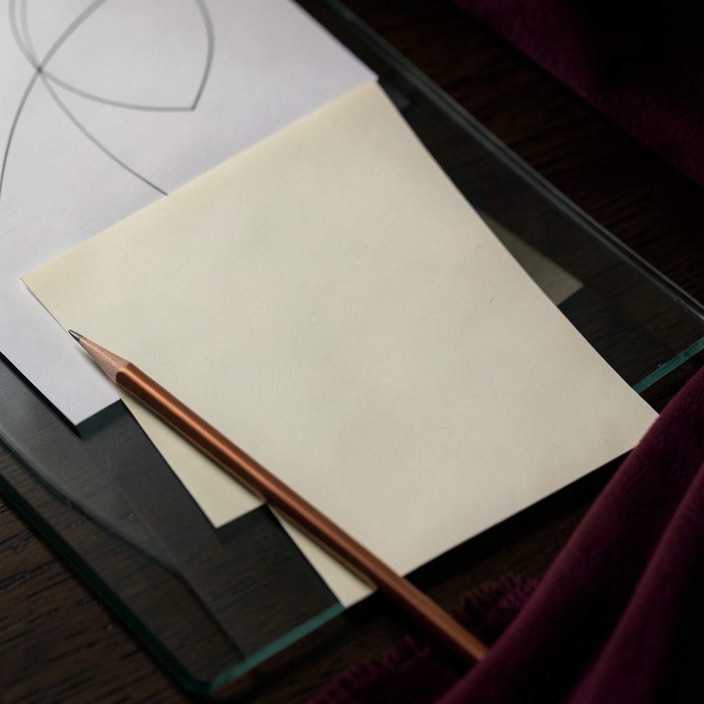 A blank cream sheet and a copper pencil on smoked glass, with the corner of an unlabeled chart